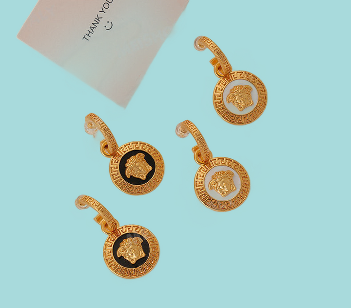 a set of three gold earrings on a blue background